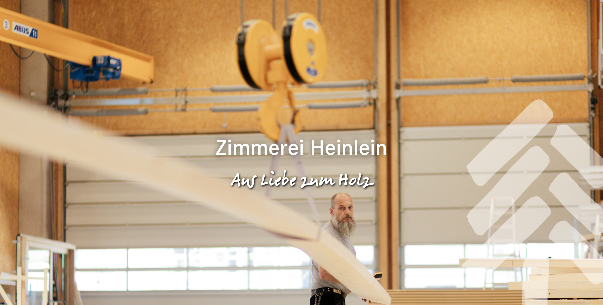 Zimmerer in der Werkstatt beim Zuschnitt eines Holzbalkens – moderner Holzbau der Zimmerei Heinlein in Neustadt an der Aisch